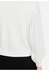 Felpa bianca con maniche strutturate e arricciate adornate da paillettes argentate verticali. Il bordo e i polsini a coste offrono una forma aderente.