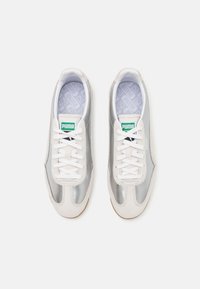 Baskets Puma avec une tige synthétique argentée, des lacets blancs et une semelle intérieure grise texturée. Caractérisées par une semelle en caoutchouc et des accents de logo verts.