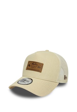 Beige New Era adjustable cap with brown leather brand patch on front and mesh back panel, angled to show curved brim and side logo.