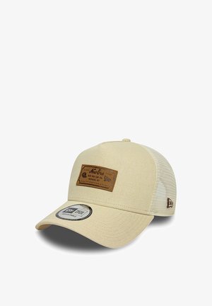 Beige New Era verstellbare Kappe mit braunem Leder-Brandpatch vorne und Netzrücken, schräg gezeigt, um die gebogene Krempe und das Seitenlogo zu zeigen.