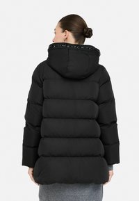 Čierna puffa bunda s kapucňou, s prešívaným dizajnom, texturovanou tkaninou a elastickými detailami okolo výstrihu kapucne.