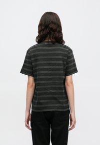 Krátký rukáv, tmavě šedé tričko s horizontálními pruhy. Vyrobeno z měkké tkaniny s kulatým výstřihem a uvolněným střihem. Jednoduchý, texturovaný design.