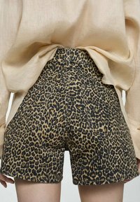 Traperice s leopard uzorkom, visoki struk, stražnji džepovi i teksturirana tkanina. Paleta boja uključuje bež i crne uzorke.