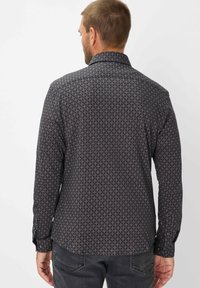 Camicia da uomo a fantasia scura con un design geometrico in tonalità di blu, ruggine e crema, con maniche lunghe e colletto classico.