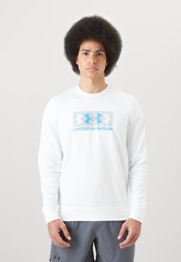 Sudadera blanca de manga larga con el logo de Under Armour en gris y azul en el pecho. Tejido suave con puños y dobladillo acanalados.