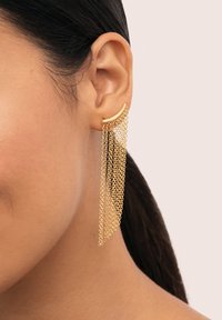 Los pendientes de cadena dorada presentan una barra curvada con múltiples hebras en cascada. Tienen una textura suave y un acabado brillante.