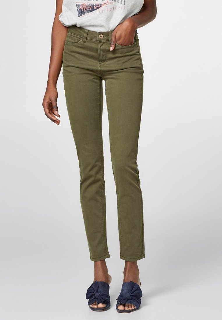 Pantalon slim fit vert olive porté avec un t-shirt imprimé décontracté et des sandales ouvertes bleu marine à enfiler avec des détails en nœud.
