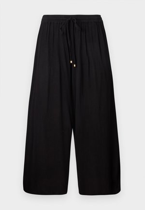 Schwarze weit geschnittene Hosen aus einem strukturierten Stoff. Mit einem elastischen Bund und einem Kordelzug sowie goldfarbenen Akzenten an den Enden.