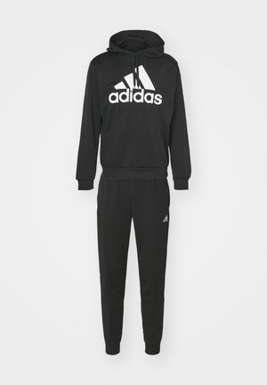 Sweatshirt à capuche noire et pantalon assorti en tissu doux avec un grand logo blanc adidas à l'avant et un petit logo sur la jambe du pantalon.