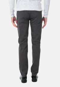 Pantaloni grigi con una vestibilità dritta, caratterizzati da una texture liscia, tasche posteriori standard, indossati con scarpe nere e un maglione chiaro.