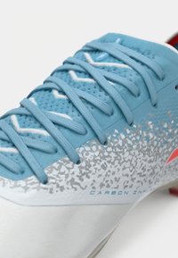Blue and white sneaker with light blue laces, gray speckled pattern, and red logo, showing upper and midsole detail.