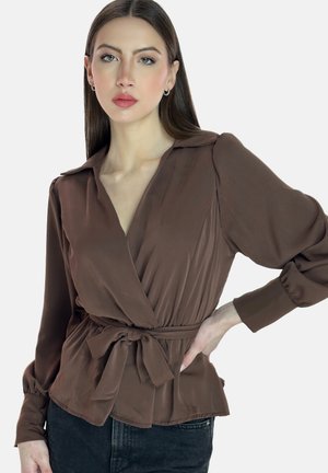 Blouse marron à manches longues avec un détail de taille nouée, présentant une texture douce et lisse ainsi qu'un col structuré.
