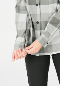 Grå og hvid ternet skjorte med sorte knapper, lange ærmer og manchetter med knapper; stoffet ser blødt ud med en let struktureret overflade.