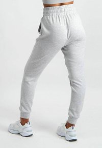 Grijze katoenen joggingbroeken met een elastische tailleband, taps toelopende enkels, zijzakken en een zachte textuur, gecombineerd met witte sportschoenen.
