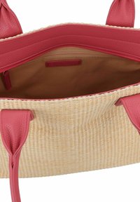 Bolso de tote de paja tejido con un exterior suave en beige y asas y acentos de cuero rojo vibrante. Interior forrado en una tela lisa en tono marrón.