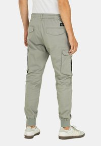 Helle graue Cargo-Hosen mit elastischem Bund, Seitentaschen und gerippten Bündchen. Hergestellt aus einem strapazierfähigen, glatten Stoff.