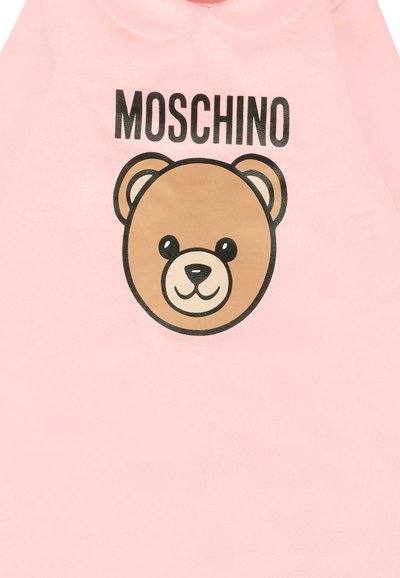 Pink sweatshirt with a bear graphic in browns, featuring the brand name "MOSCHINO" above the design in black lettering. Smooth texture.