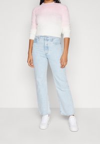 Jasnoróżowy i biały miękki sweter z okrągłym dekoltem, zestawiony z jasnoniebieskimi, wysokim stanem, prostymi spodniami dżinsowymi oraz białymi trampkami.