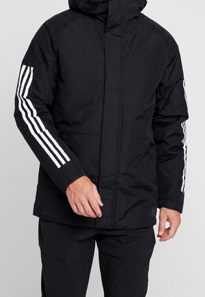 Veste matelassée noire avec col montant, fermeture éclair frontale, accents blancs à trois bandes sur les manches, et une texture légère et lisse.