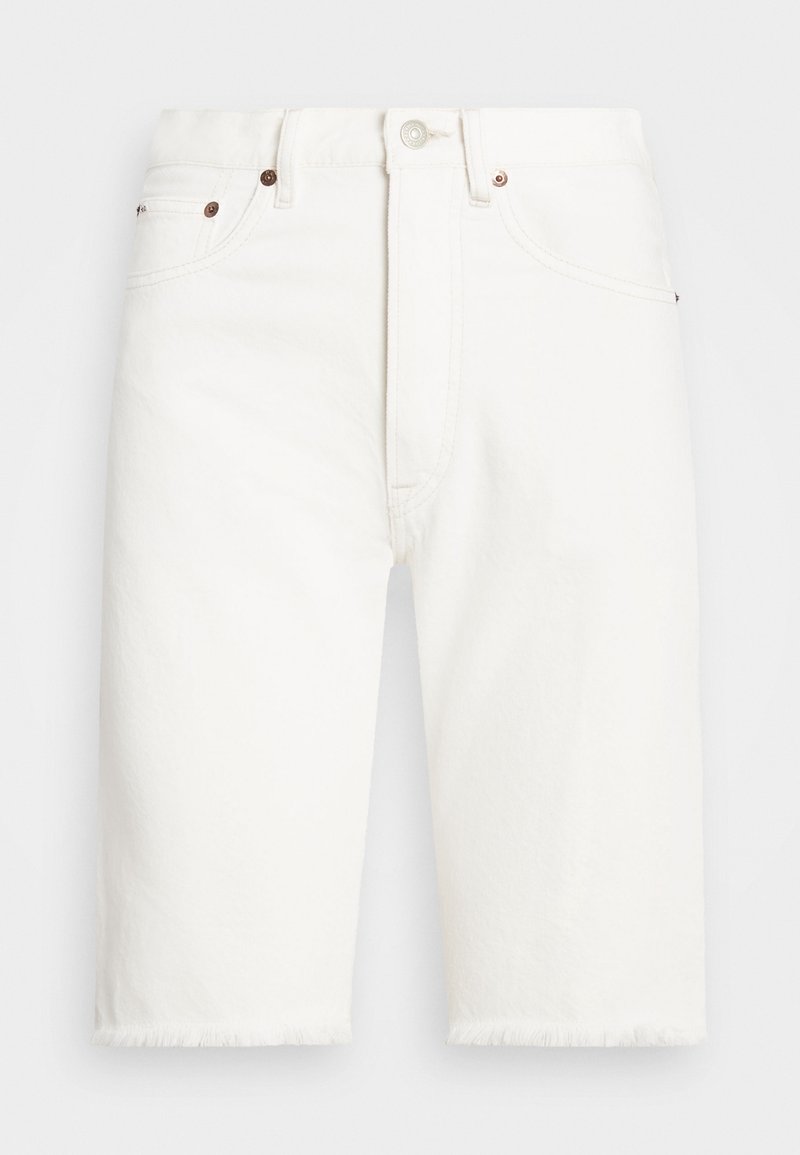 Valkoiset farkkushortsit, joissa on rispaantunut helma, viis-taskuinen malli, kevyt tekstuuri ja pronssinväriset metalliosat edessä.