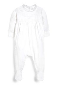 Vitt nyfött jumpr för barn tillverkat av mjukt tyg, med rund halsringning med spetskant, långa ärmar och ben som har fötter. Dekorerad broderi på bröstet.