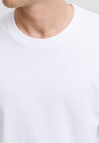 Wit katoenen T-shirt met ronde hals en een gladde textuur, met een klassieke snit en een geribbelde kraag, met lichte variaties in de stof.