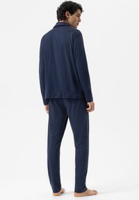 Ensemble de pyjama en coton bleu marine comprenant un haut à manches longues avec col et un pantalon assorti, tissu lisse, coupe décontractée et sans motifs visibles.