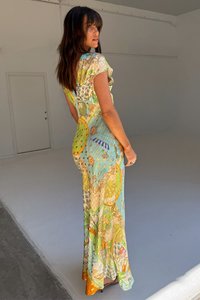 Fittelt sziluettű maxi ruha, könnyű anyagból, türkiz színben, több színből álló virág- és geometriai mintákkal.