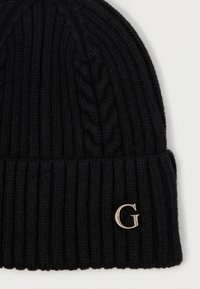 Musta neulottu pipo, jossa on ribbikuvio ja punottu malli. Etupuolella on hopeinen "G"-logo. Sopii kylmempiin ilmastoihin.