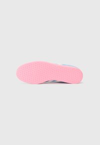 Semelle de chaussure en caoutchouc rose avec un motif en nid d'abeille, présentant des accents bleu clair et blanc. Texture lisse, forme arrondie et design flexible.