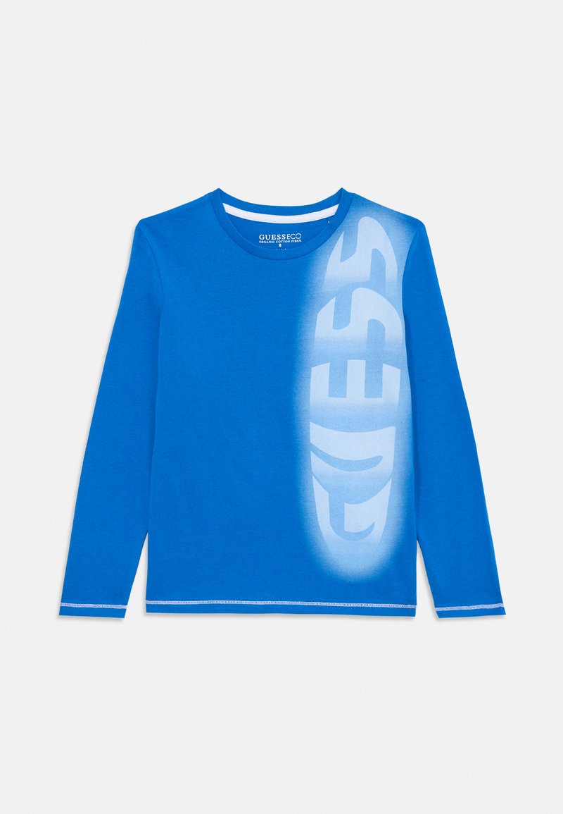 Blaues Langarm-T-Shirt aus Baumwolle, mit einem großen weißen Verlauf-"GUESS"-Logo auf der Vorderseite und kontrastierenden blauen Nähten an den Ärmeln.