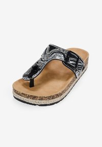 Sandalo flip-flop nero decorato con una suola spessa, dotato di perline decorative e un sottopiede in sughero texturizzato. Morbido fondo interno.