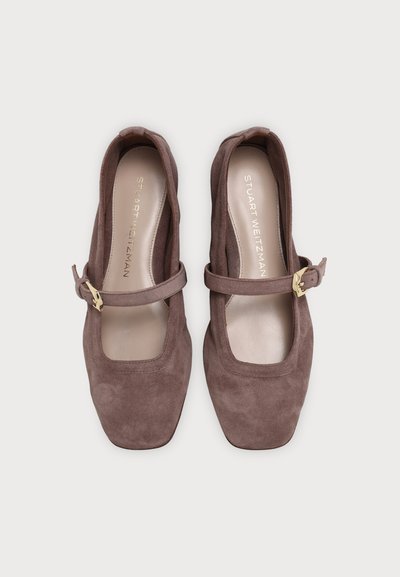 Paire de chaussures style Mary Jane en daim marron avec bouts carrés et brides à boucle dorée, vue de dessus sur un fond uni.
