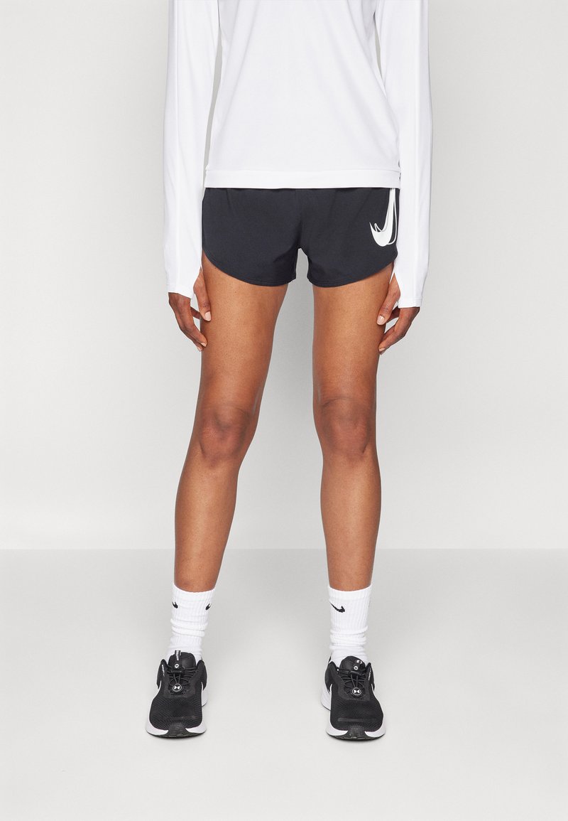 Mustad mustrikad musta Nike ümmarguse logoga. Kantud koos pikakäiselise valge topiga, mustade spordijalatsite ja valgete sokkidega.