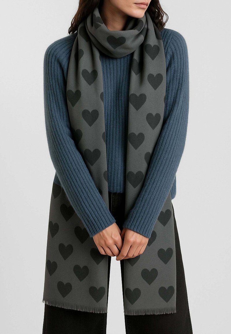 Sciarpa grigia con motivo a cuori ripetuti in grigio scuro, realizzata in materiale morbido, con bordi frangiati, drappeggiata intorno al collo.