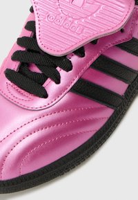Rosa satin sneakers med svarta läderstripes, texturerad svart gummisula och kontrasterande svarta snörningar. Har en ribbad rosa tunga.