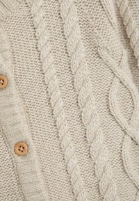 Světle béžový pletený cardigan s žebrovanými manžetami a vzorem z kabelového úpletu, se dřevěnými knoflíky podél zapínání.