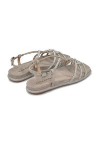 Sandalias de material de ante beige, con acentos de purpurina plateada, tiras entrelazadas y una suela plana con cierre de hebilla.