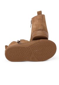 Rudi suede auliniai batai su šoniniu užtrauktuku, guminėmis padomis, turinčiomis zigzago raštą, ir su dirželiu nugarinėje dalyje, kad juos būtų lengva užsidėti.