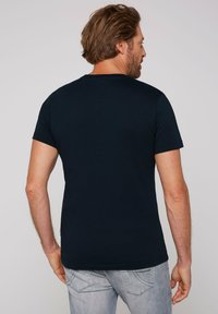 Granatowa bawełniana koszulka z krótkim rękawem, okrągłym dekoltem i regularnym krojem. Widoczny detal szwu na dolnej krawędzi.