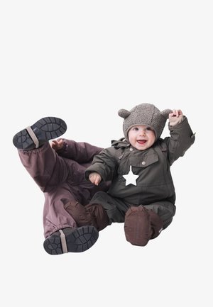 To barn i matchende vinterdresser. Den ene har på seg en grønn dress med brune detaljer, en stjerne-pendante og en grå bjørnelue. Den andre har på seg lilla.