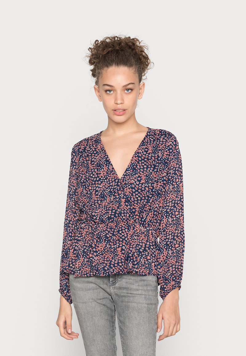 Blusa floreale blu navy con maniche lunghe e scollatura a V profonda. Presenta una vita arricciata e piccoli motivi floreali rosa e bianchi.