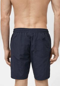 Shorts de bain bleu marine avec une taille élastique, un tissu texturé et une poche arrière avec un œillet bleu en accent.