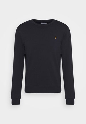 Sweatshirt noir à manches longues, avec des poignets et une taille côtelés, affichant un petit logo jaune sur la poitrine. Fabriqué en tissu doux.