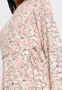 Lehká růžová šaty s květinovým vzorem v černém kontuře. Měkká textura látky se stahovací detaily v pase a volnými rukávy.