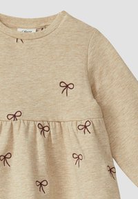 Beżowa sukienka z długim rękawem, z marszczonym pasem i haftem z bordową kokardą. Miękka, teksturowana tkanina z okrągłym dekoltem.