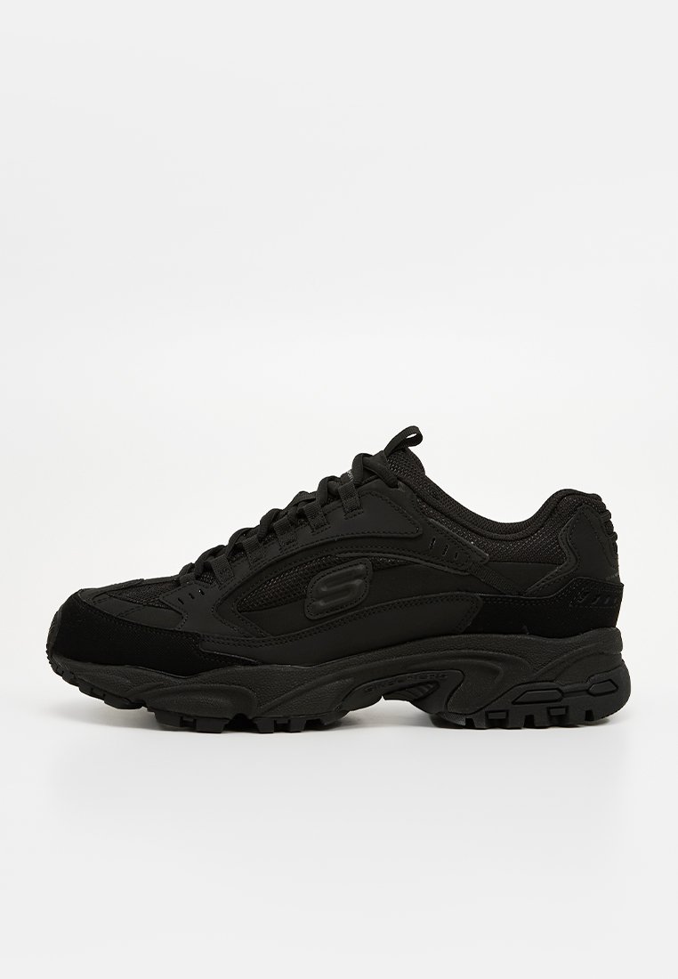 Baskets de sport noires Skechers avec un laçage à l'avant, semelle texturée et détails en maille et cuir sur le dessus, présentées en vue de profil droit.