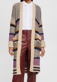 Pletený cardigan v béžové, námořnické modré a mauve s otevřeným předním dílem, dlouhými rukávy a ribbovanými manžetami. Obsahuje velké, šikmé kapsy a pruhy v různých barvách.
