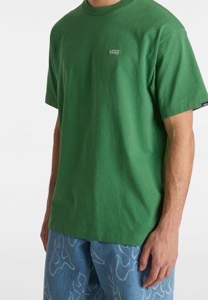 T-shirt en coton vert avec un col rond et des manches courtes, arborant un petit logo blanc sur la poitrine et une coupe décontractée.