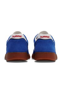 Baskets en daim bleu avec semelles en caoutchouc marron, accents blancs et logo "hummel" rouge sur le talon ; design arrondi avec une finition texturée.